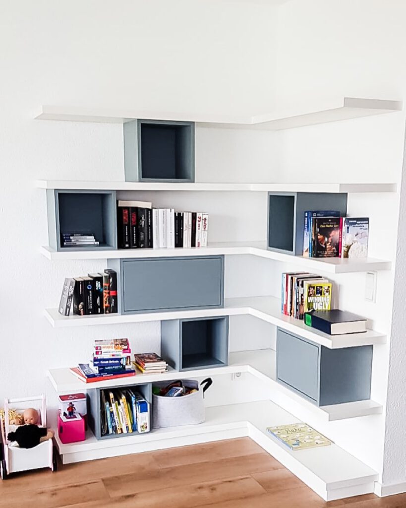 Maßgefertigtes weißes Eckregal mit grauen Box-Elementen im Wohnzimmer – Schreinerei Pass-Genau Pulheim.
