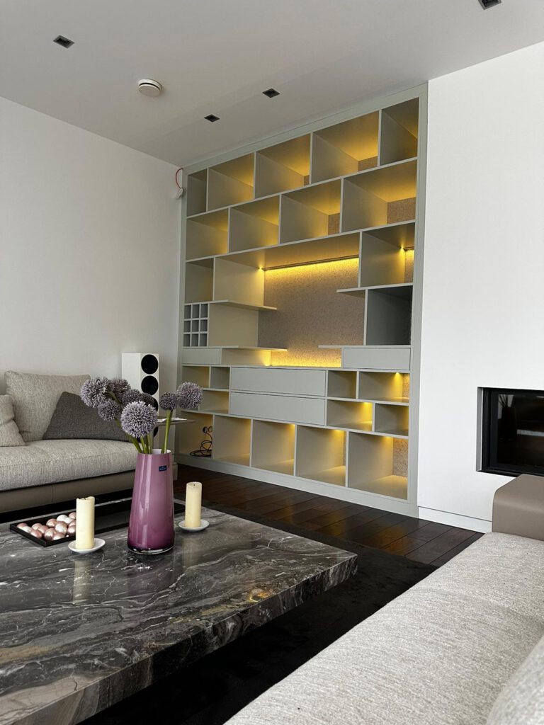 Seitenansicht einer maßgefertigten Regalwand mit Beleuchtung, die die Integration in den Wohnraum zeigt.