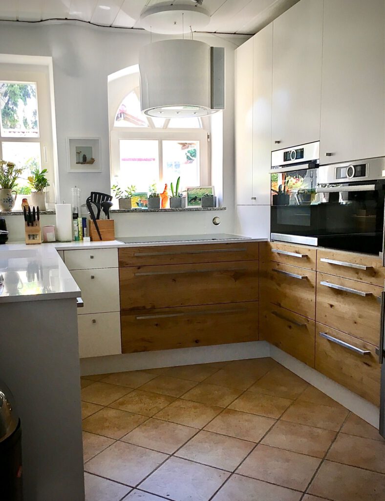 Moderne Einbauküche mit Fronten aus strukturiertem Echtholz und Weiß sowie integrierten Backöfen von Schreinerei Pass-genau.