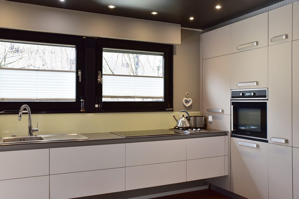 Nahaufnahme der grauen Küchenzeile mit eingelassener Spüle und Kochfeld vor einer modernen Fensterfront.