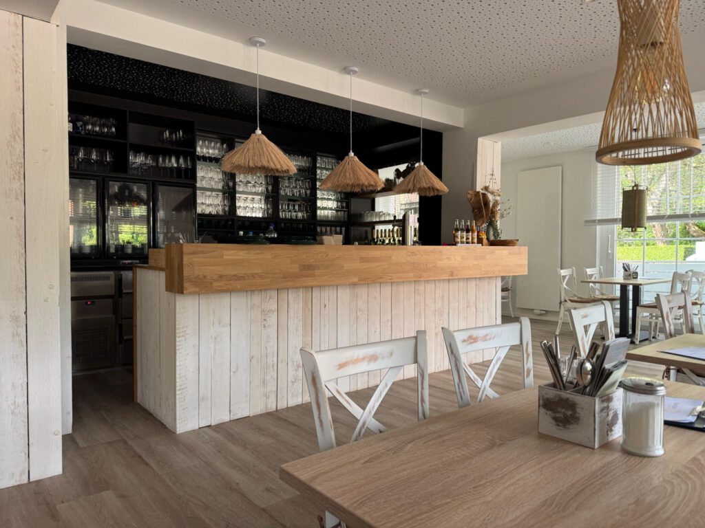 Rustikale Bartheke in heller Holzoptik mit Stroh-Hängelampen in einem modernen Restaurant.