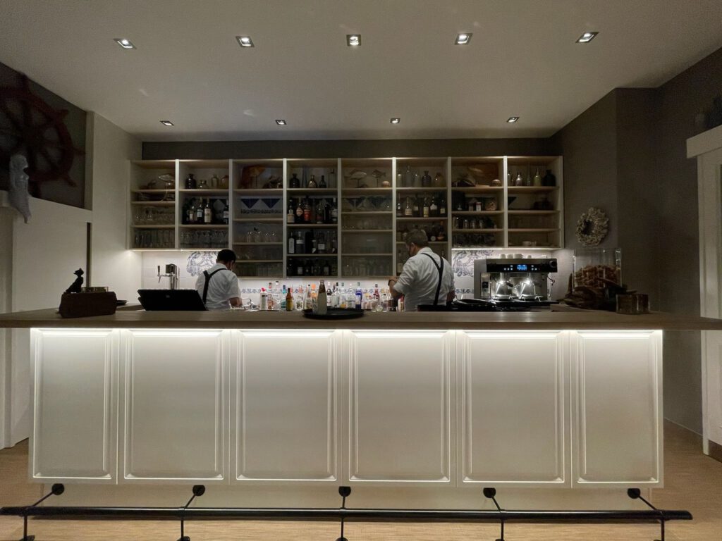 Klassisch weiße Bartheke mit Kassettenfront und Beleuchtung in einem Restaurant, gefertigt von Pass-genau.